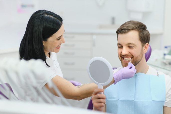 Dentist showing patient teeth whitening results in mirror at Windsor Dental Practice Leicester